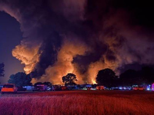 Smoke billowing high into the dark night sky illuminated by flames below
